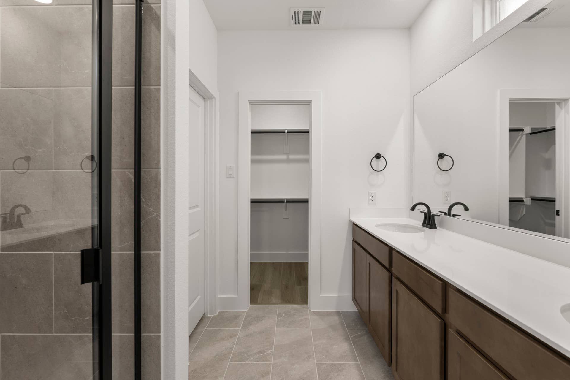Modern bathroom interior with dual sinks and glass-enclosed shower.