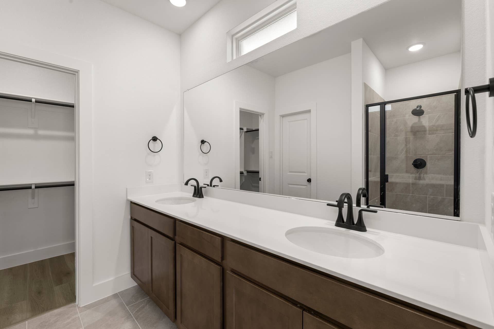 Modern bathroom with dual sinks, large mirror, and glass-enclosed shower.