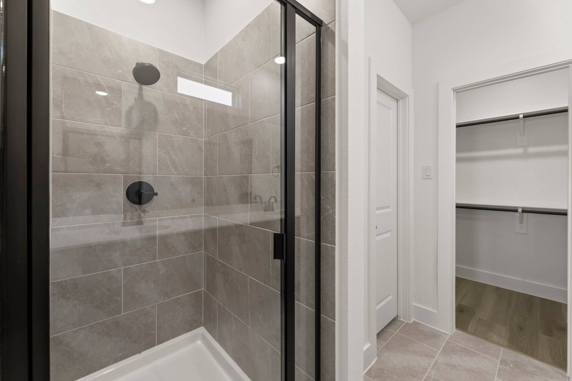 Modern bathroom with glass shower enclosure and spacious closet.