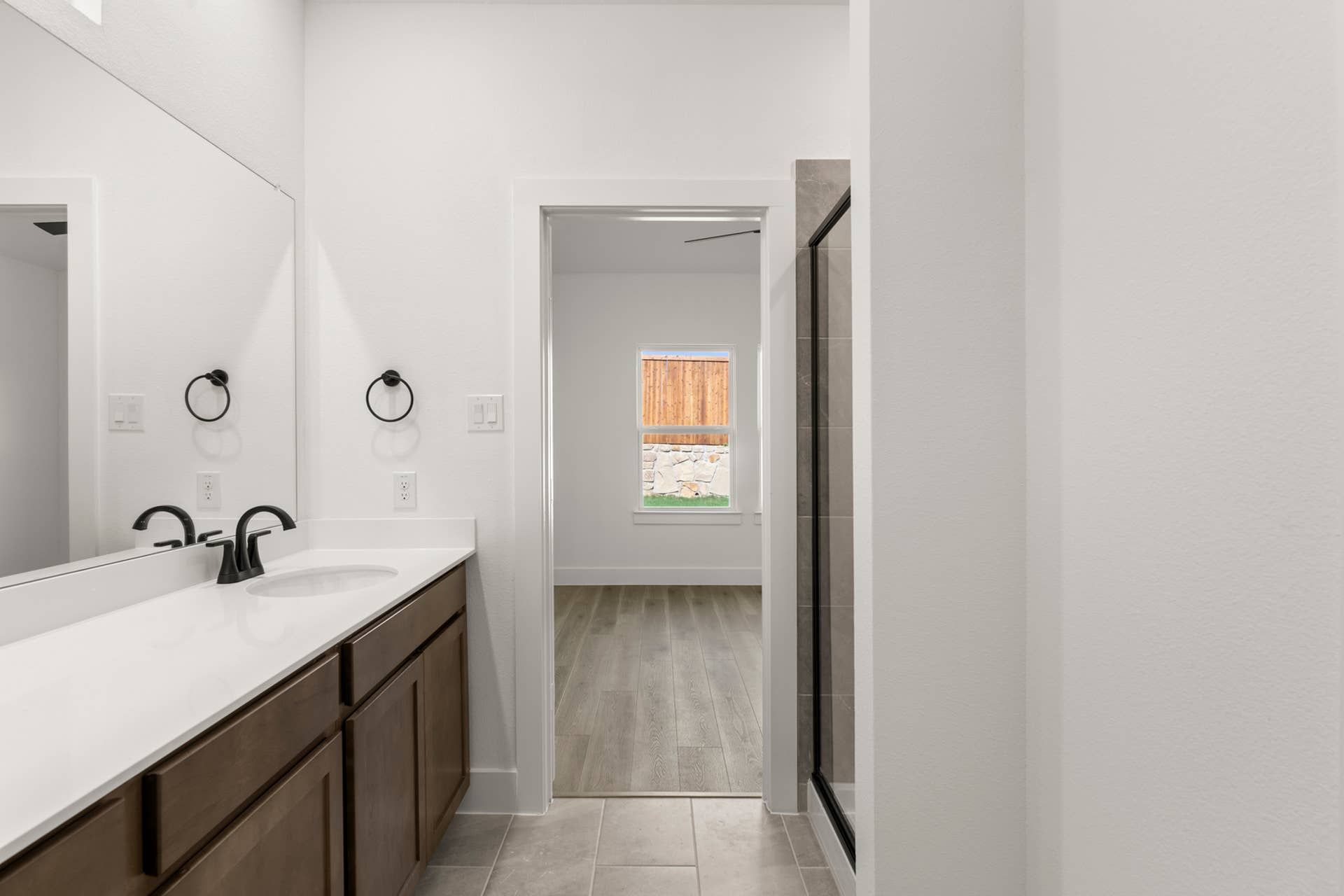 Modern bathroom with double sink vanity and adjacent shower area.