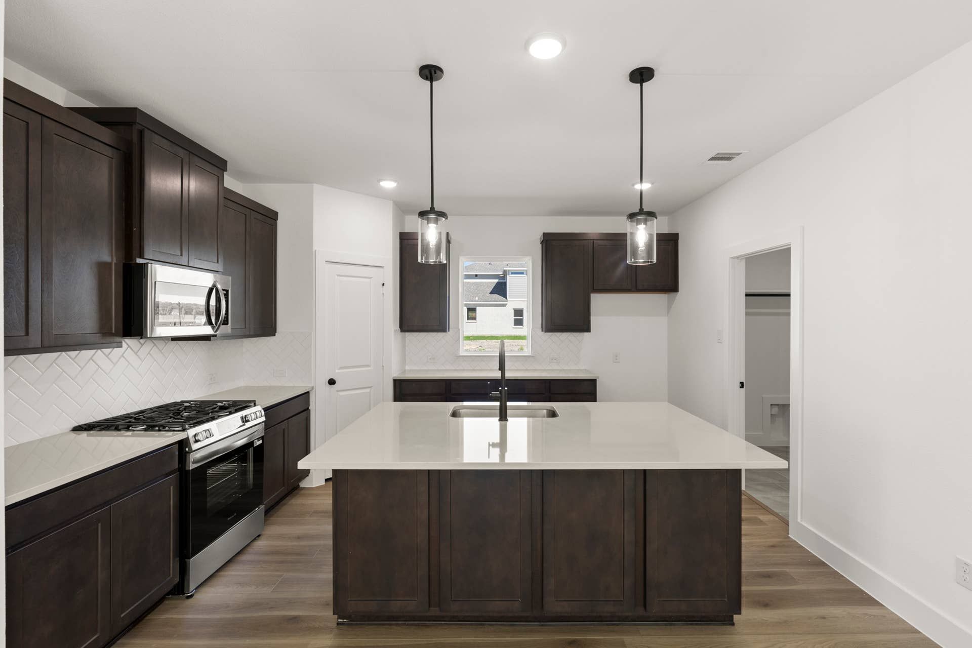Modern kitchen with dark wood cabinets, island, and pendant lighting.