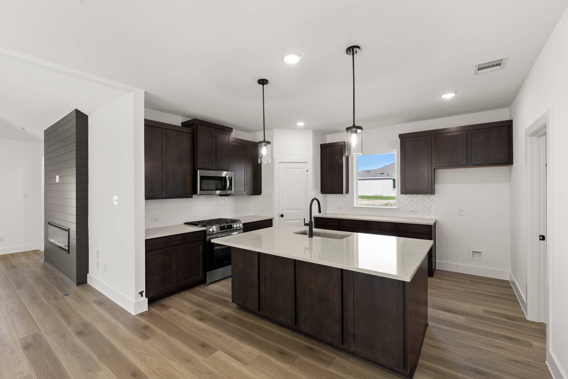 Modern kitchen with dark wood cabinets and central island.