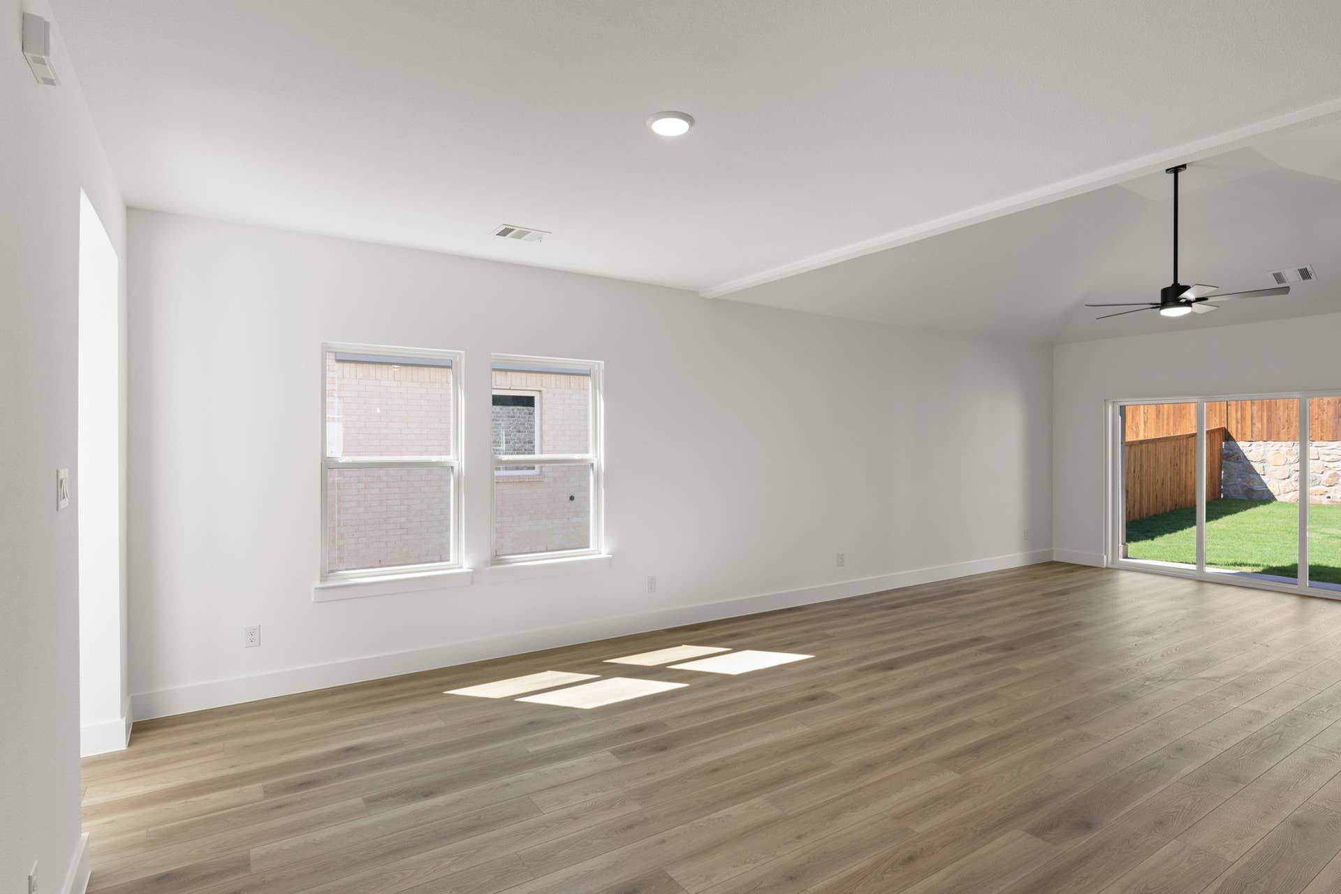 Spacious dining area with hardwood floors and large windows overlooking backyard.