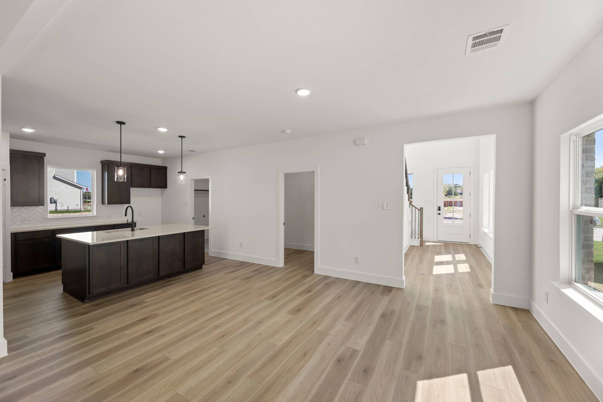 Modern open-concept kitchen and dining area with dark cabinetry and hardwood floors.
