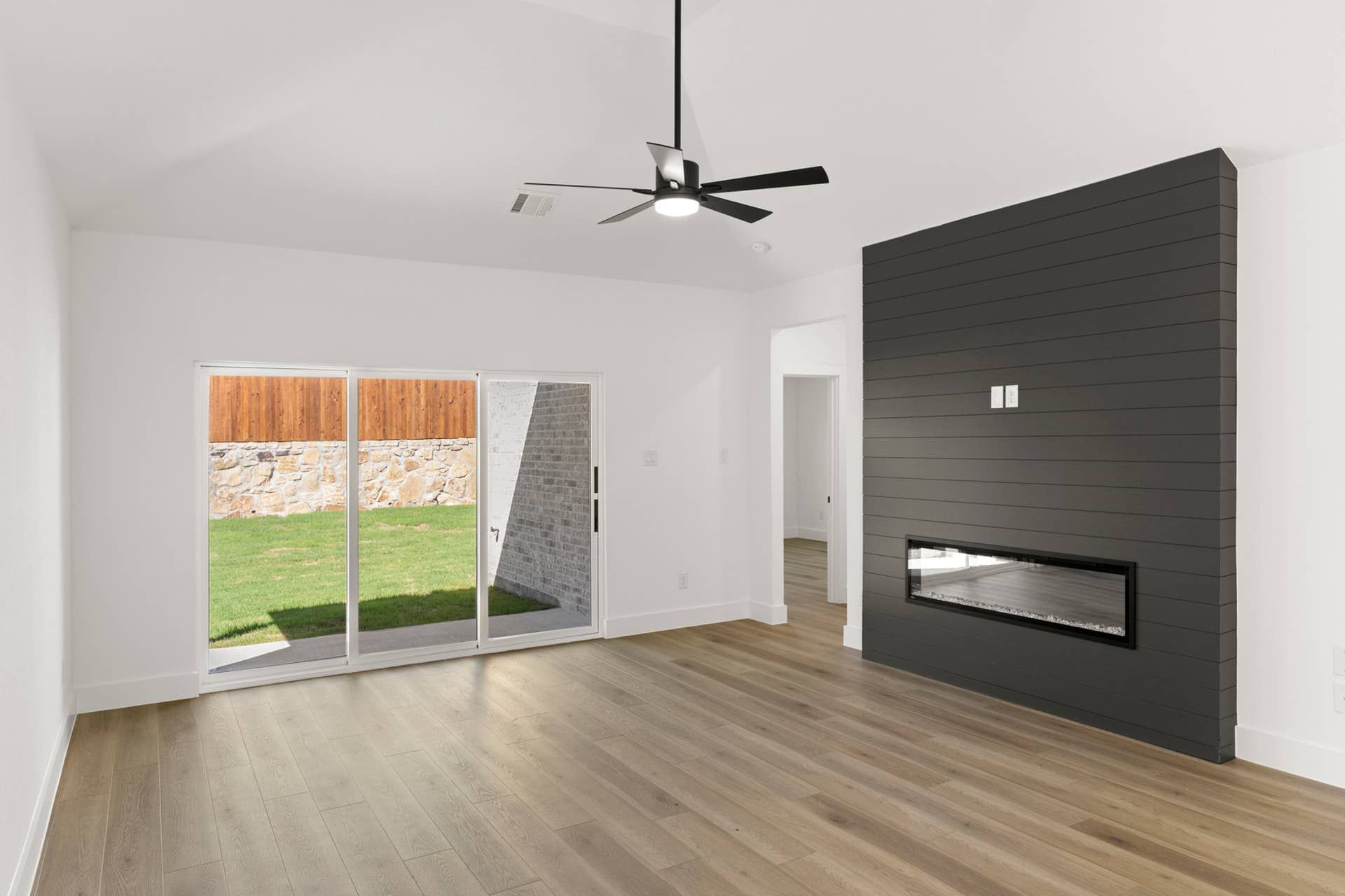 Modern living room with sliding glass doors and sleek black fireplace feature wall.