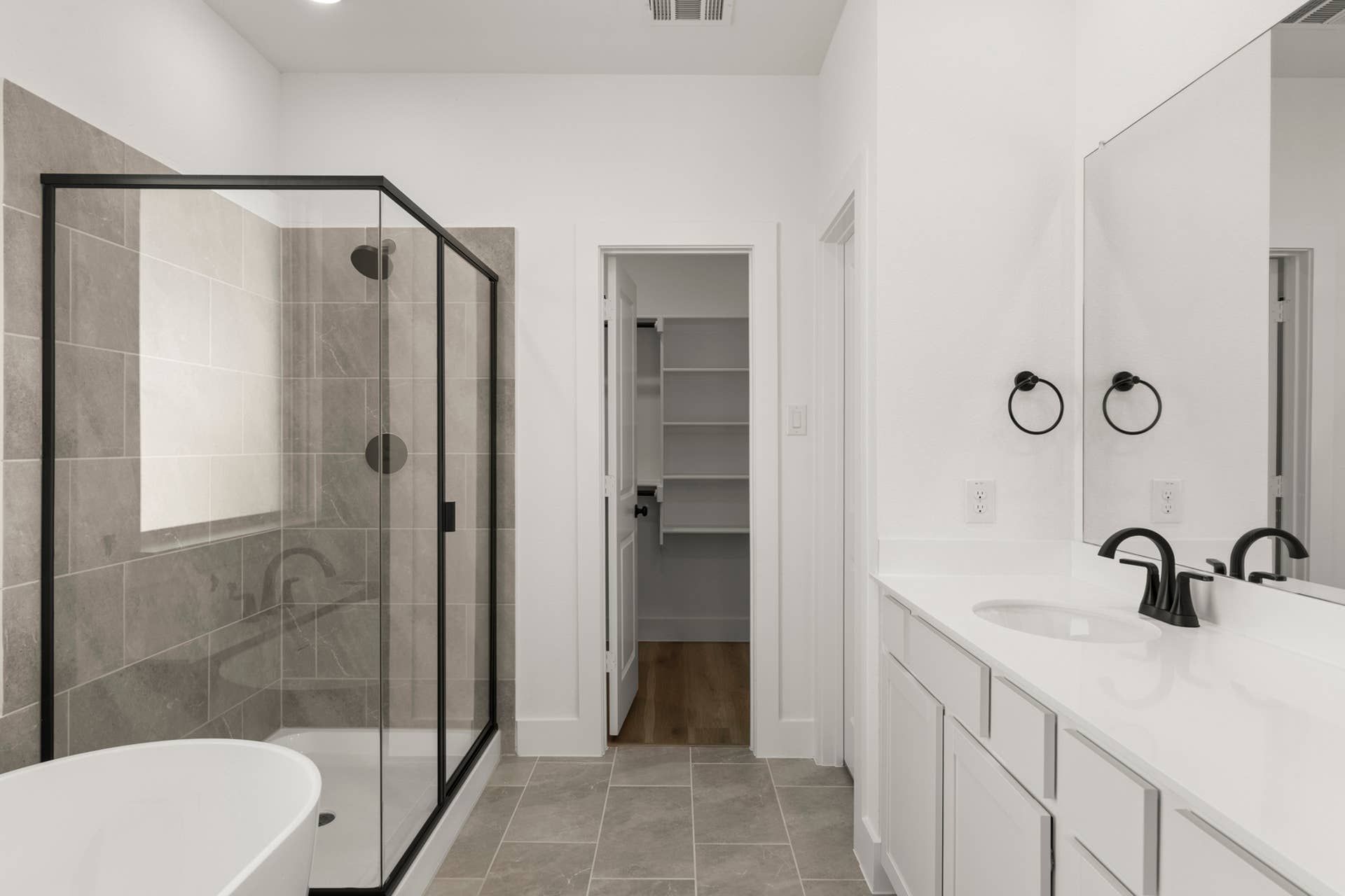 Modern bathroom with glass shower, freestanding tub, and double vanity.