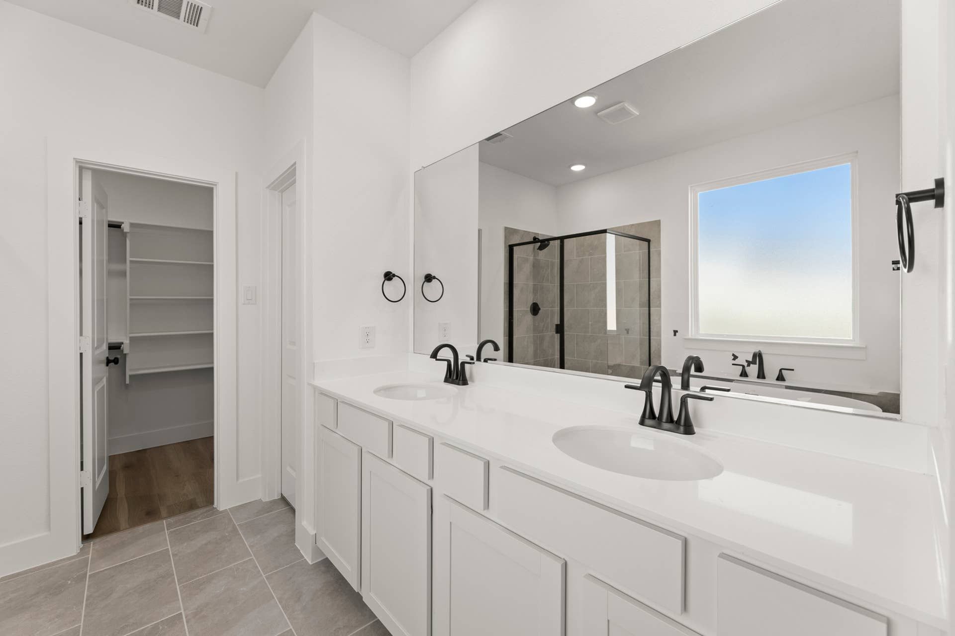 Modern bathroom with dual sinks, large mirror, and walk-in shower.