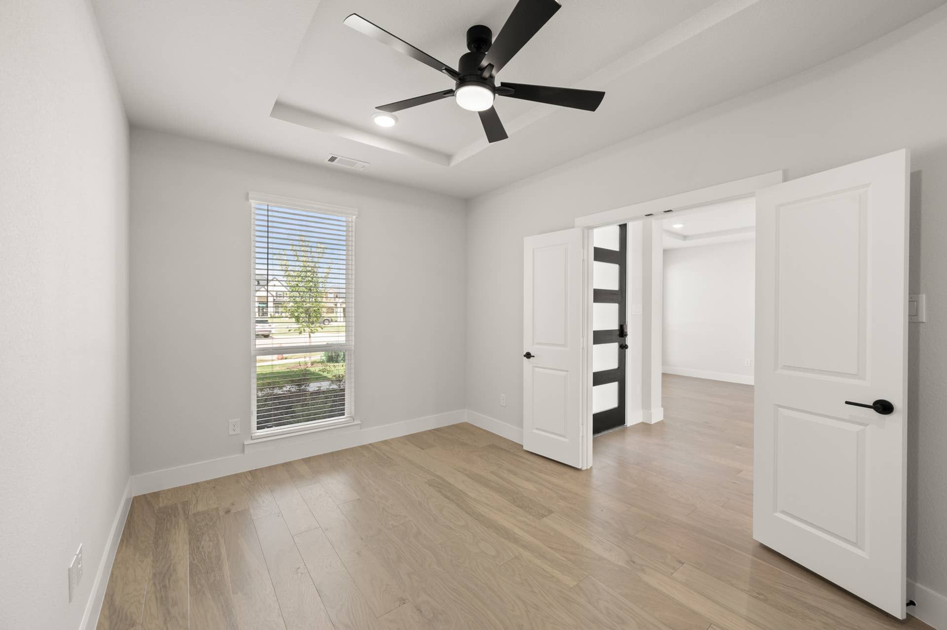 Bright study room with wood flooring and modern ceiling fan.