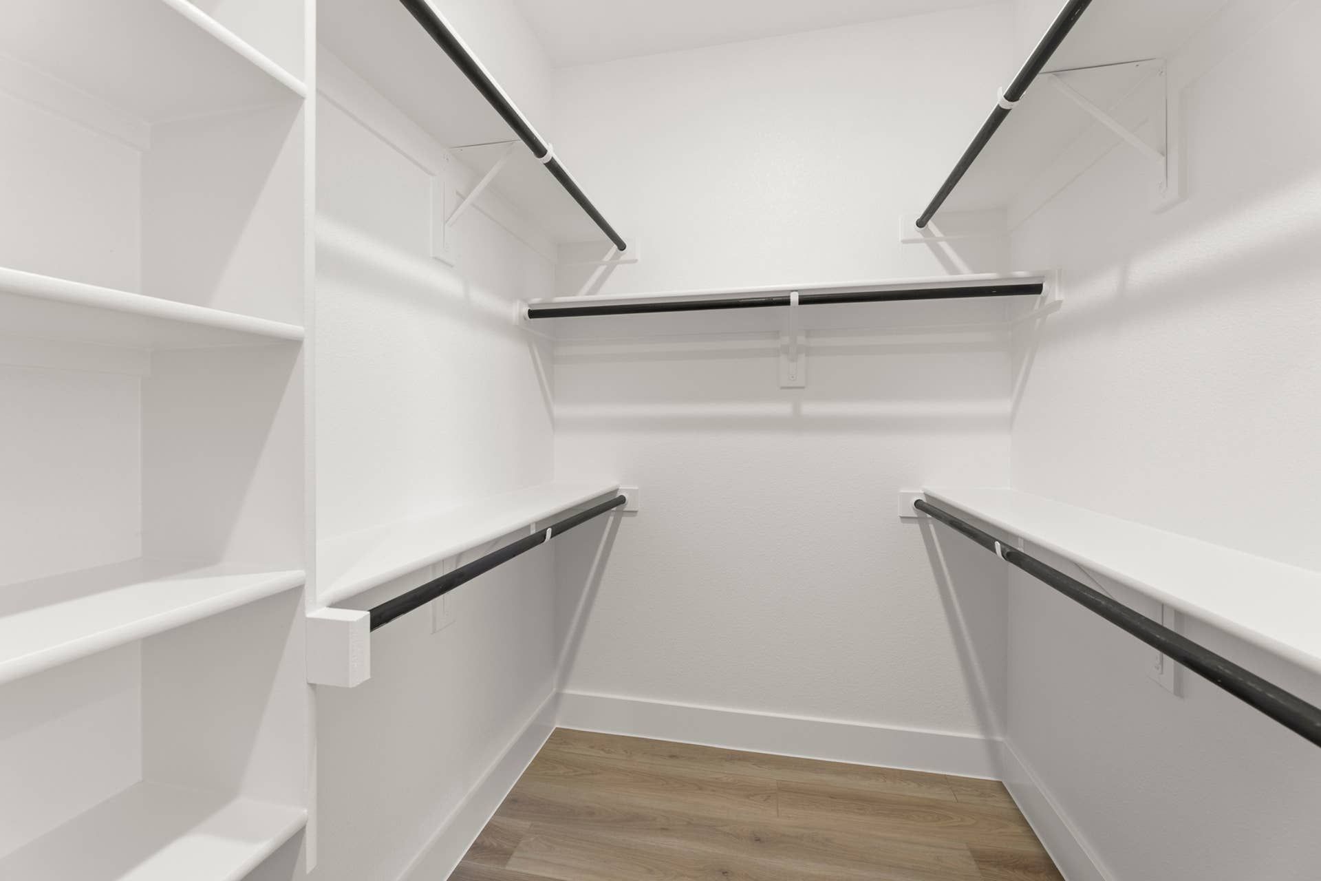 Spacious walk-in closet with white shelving and hanging rods.