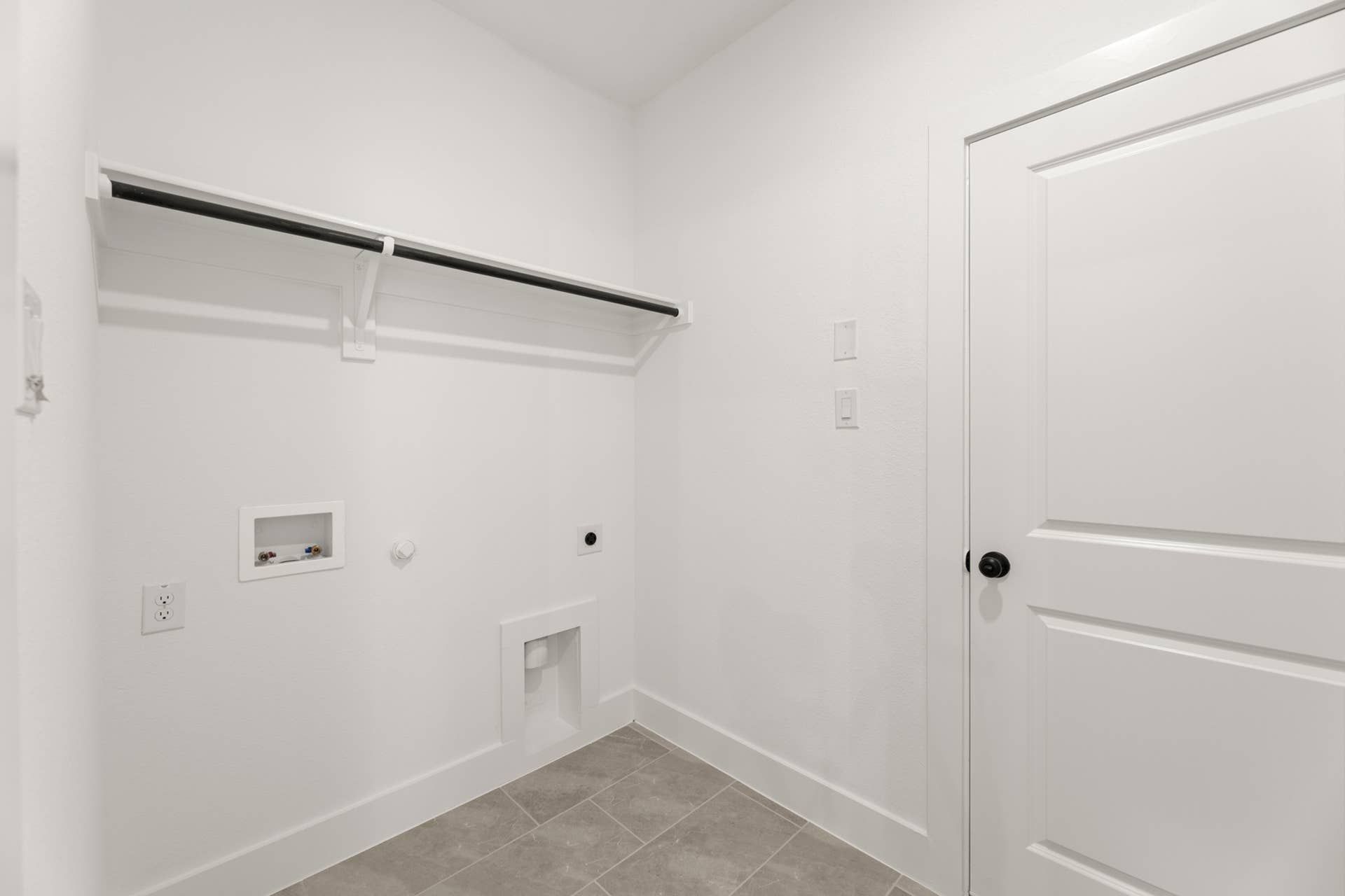 Utility room with tile flooring, shelf, and plumbing hookups.