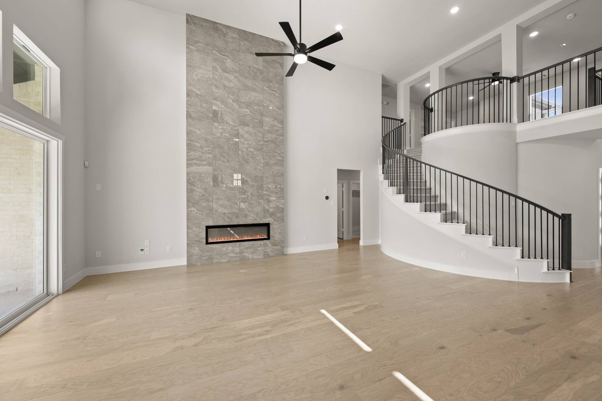 Spacious living room with modern fireplace and elegant curved staircase.