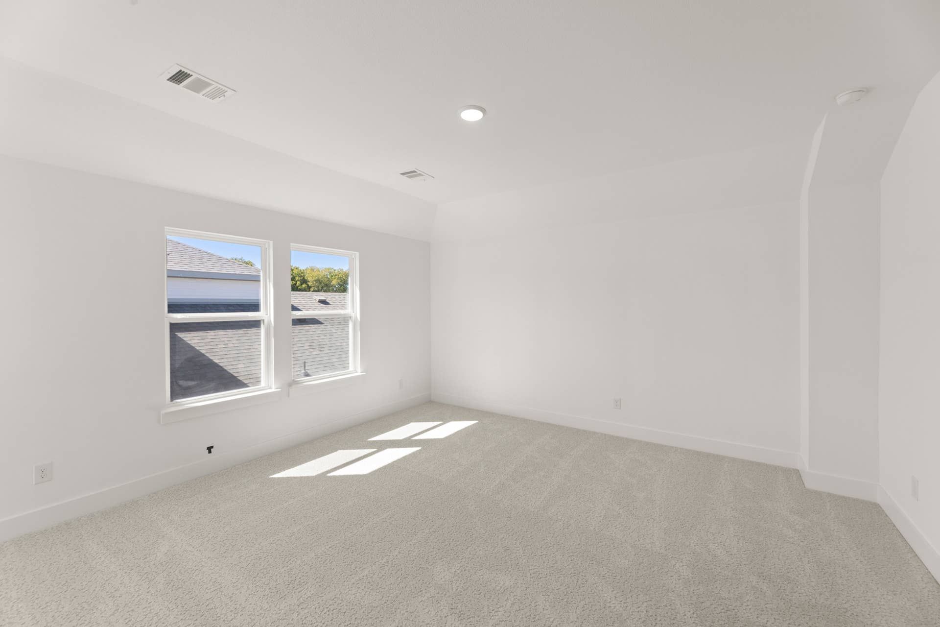 Bright, spacious room with carpeted floor and two large windows.