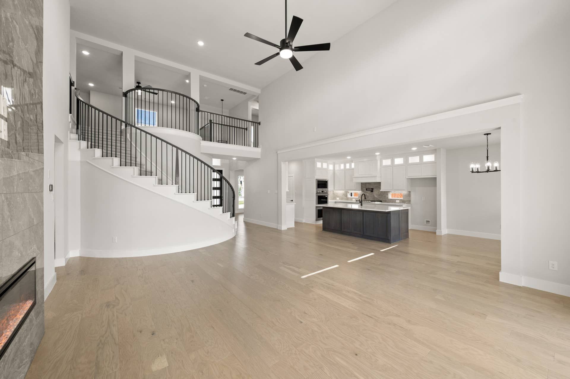 Spacious living room with spiral staircase and modern open kitchen design.