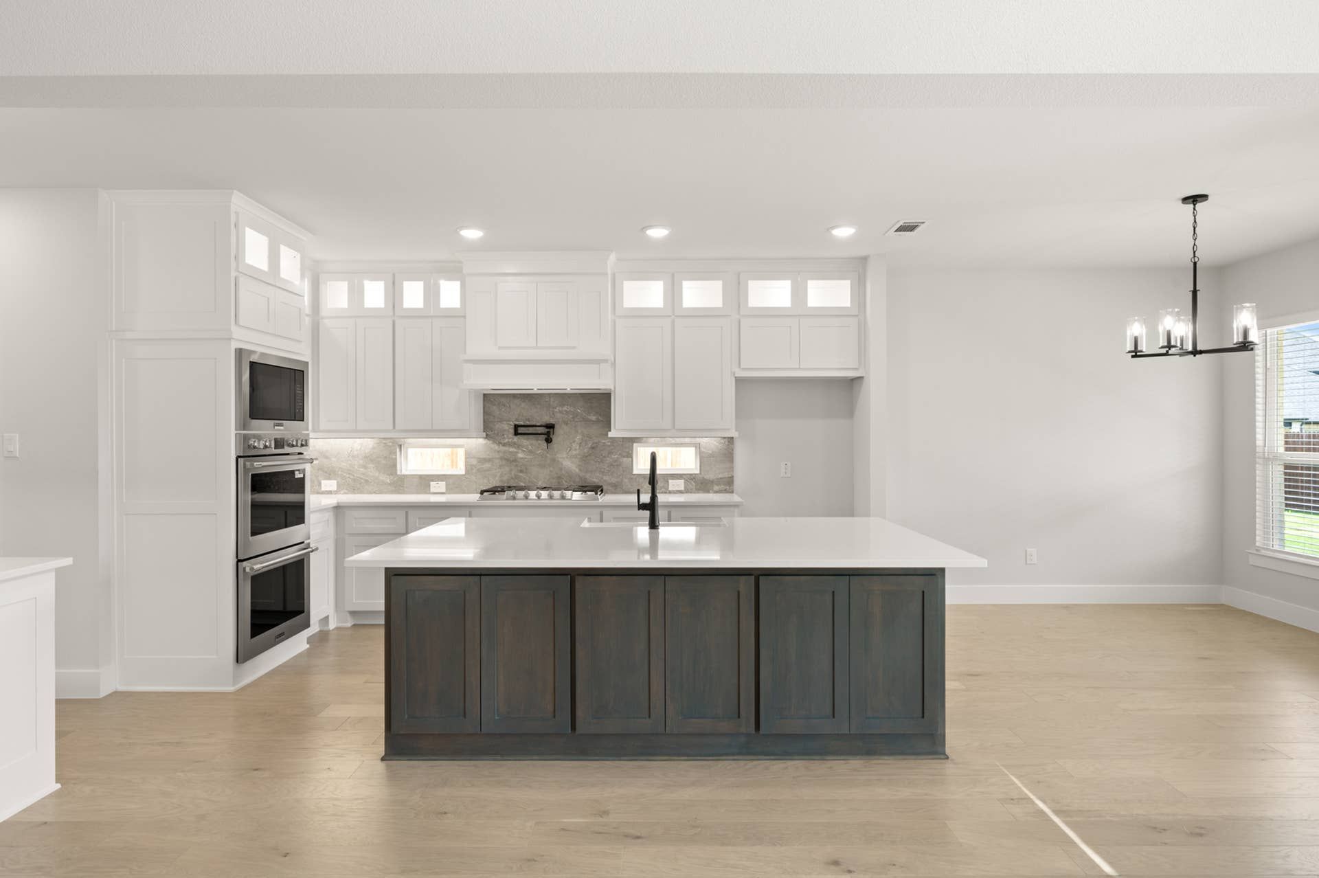Modern kitchen with large island, white cabinetry, and stainless steel appliances.