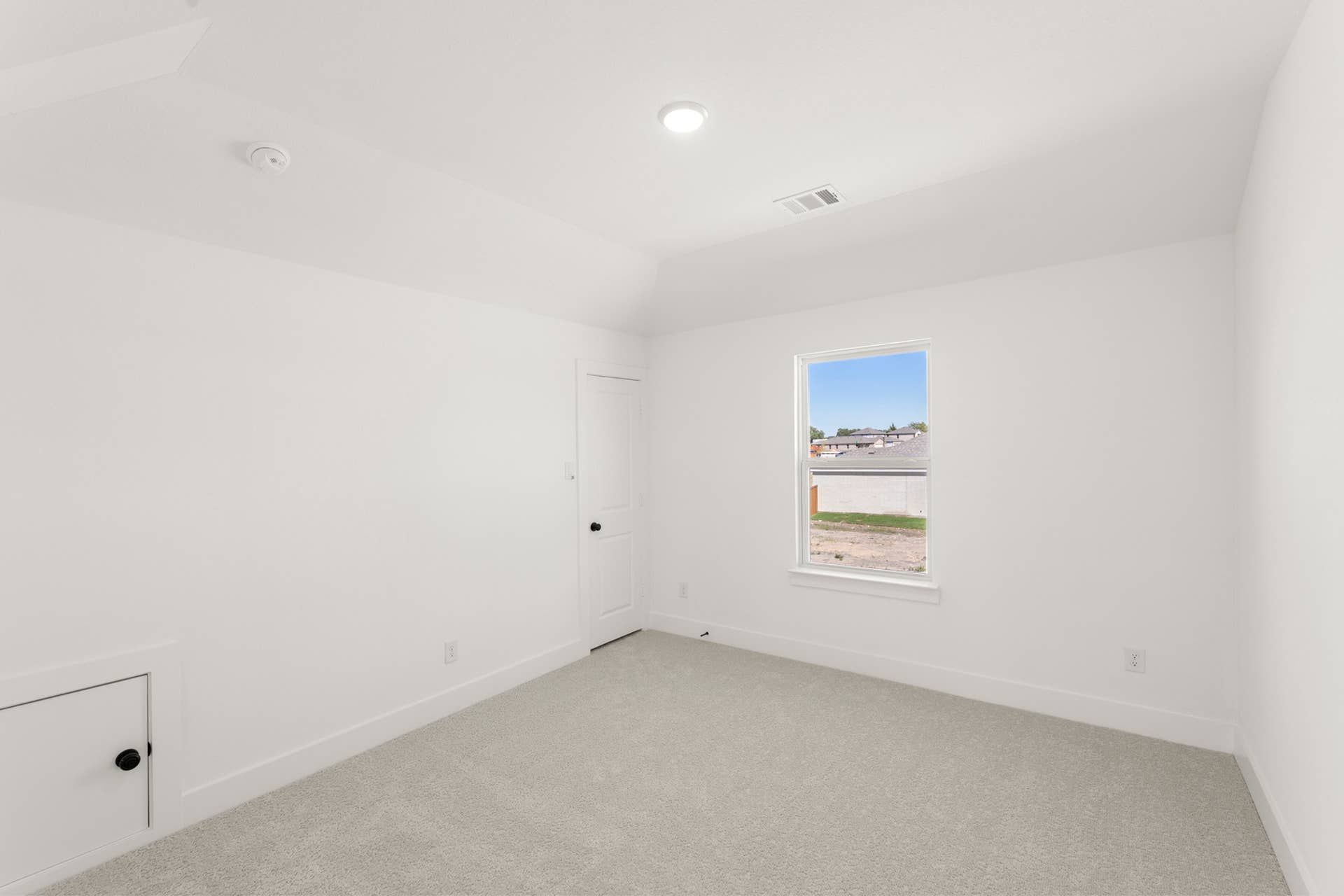 Bright, minimalist bedroom with carpet flooring and a single window.