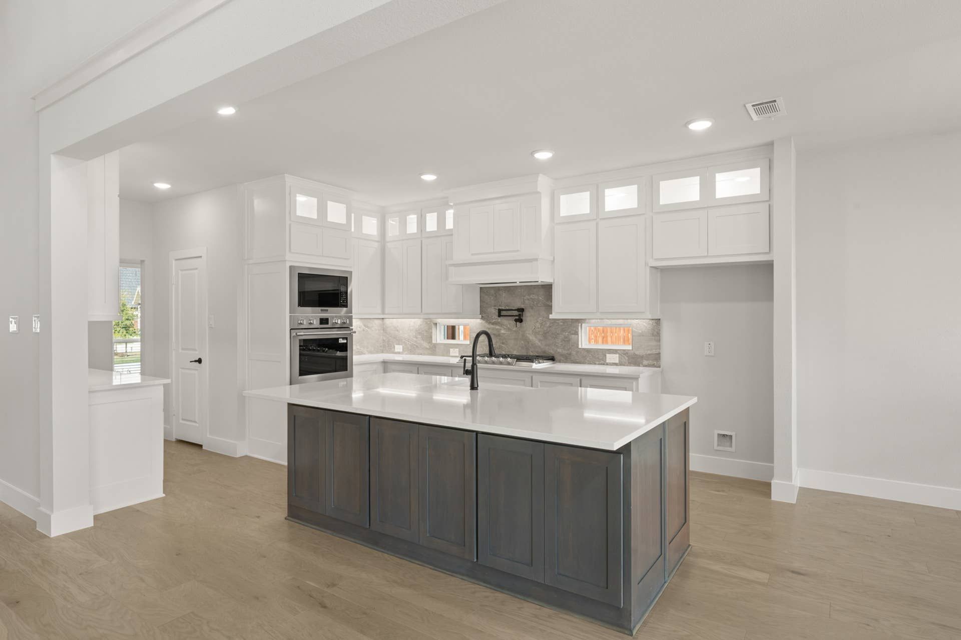 Modern kitchen with white cabinets, large island, and stainless steel appliances.