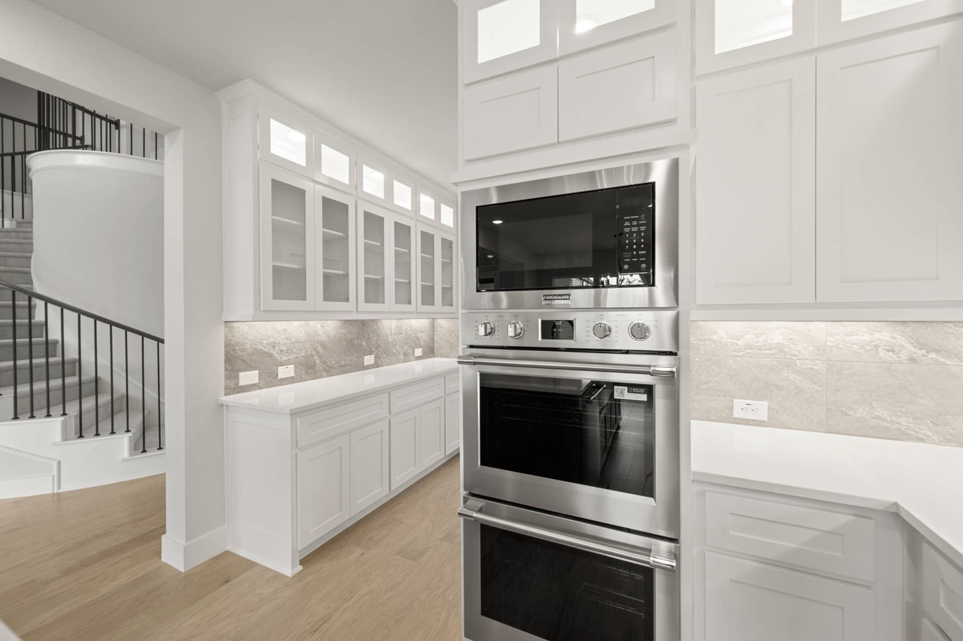 Modern kitchen with stainless steel double oven and sleek white cabinetry.