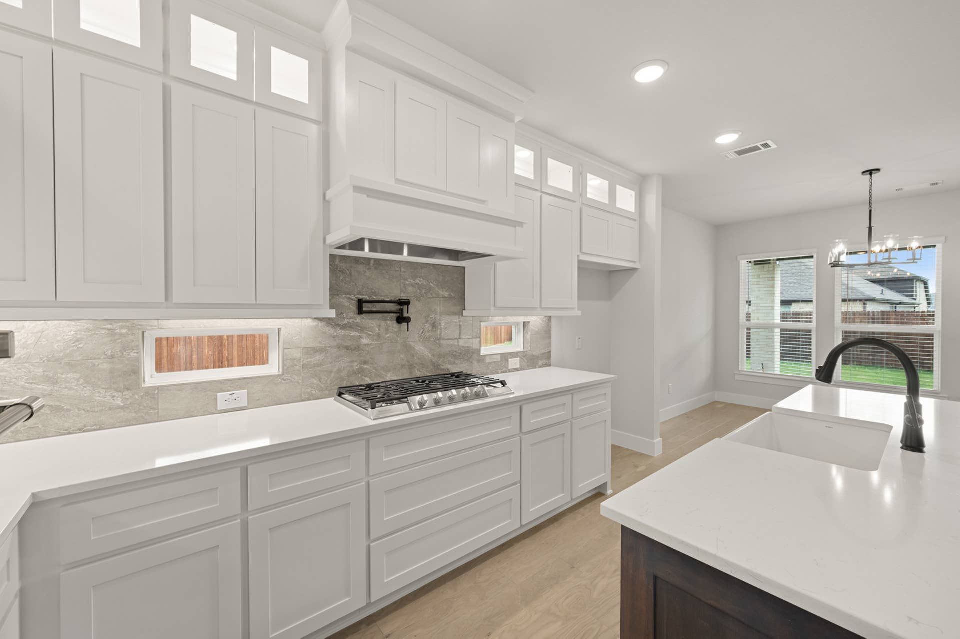 Modern kitchen with white cabinets, marble backsplash, and large farmhouse sink.