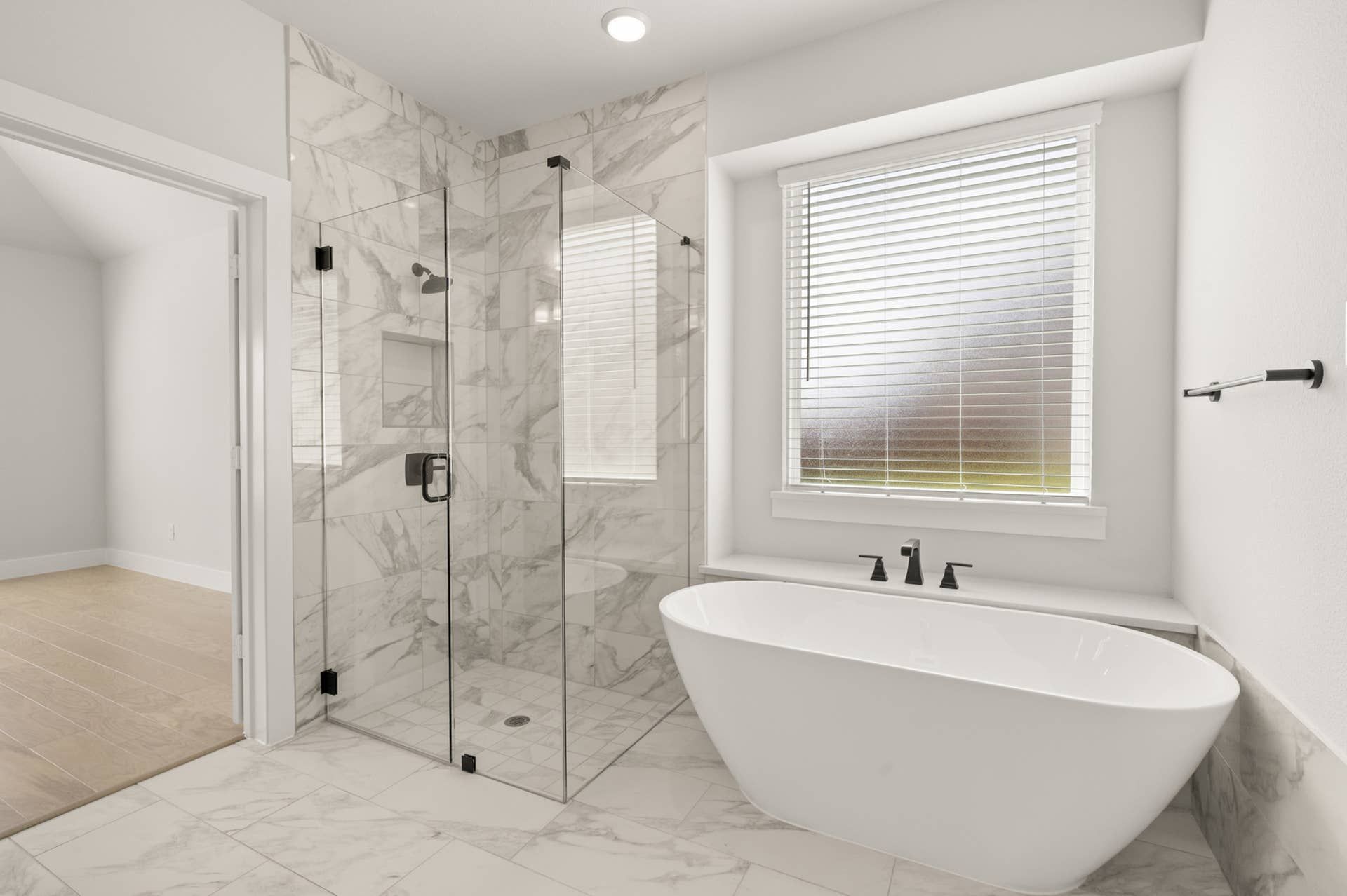 Luxurious primary suite bathroom with freestanding tub and glass-enclosed shower.