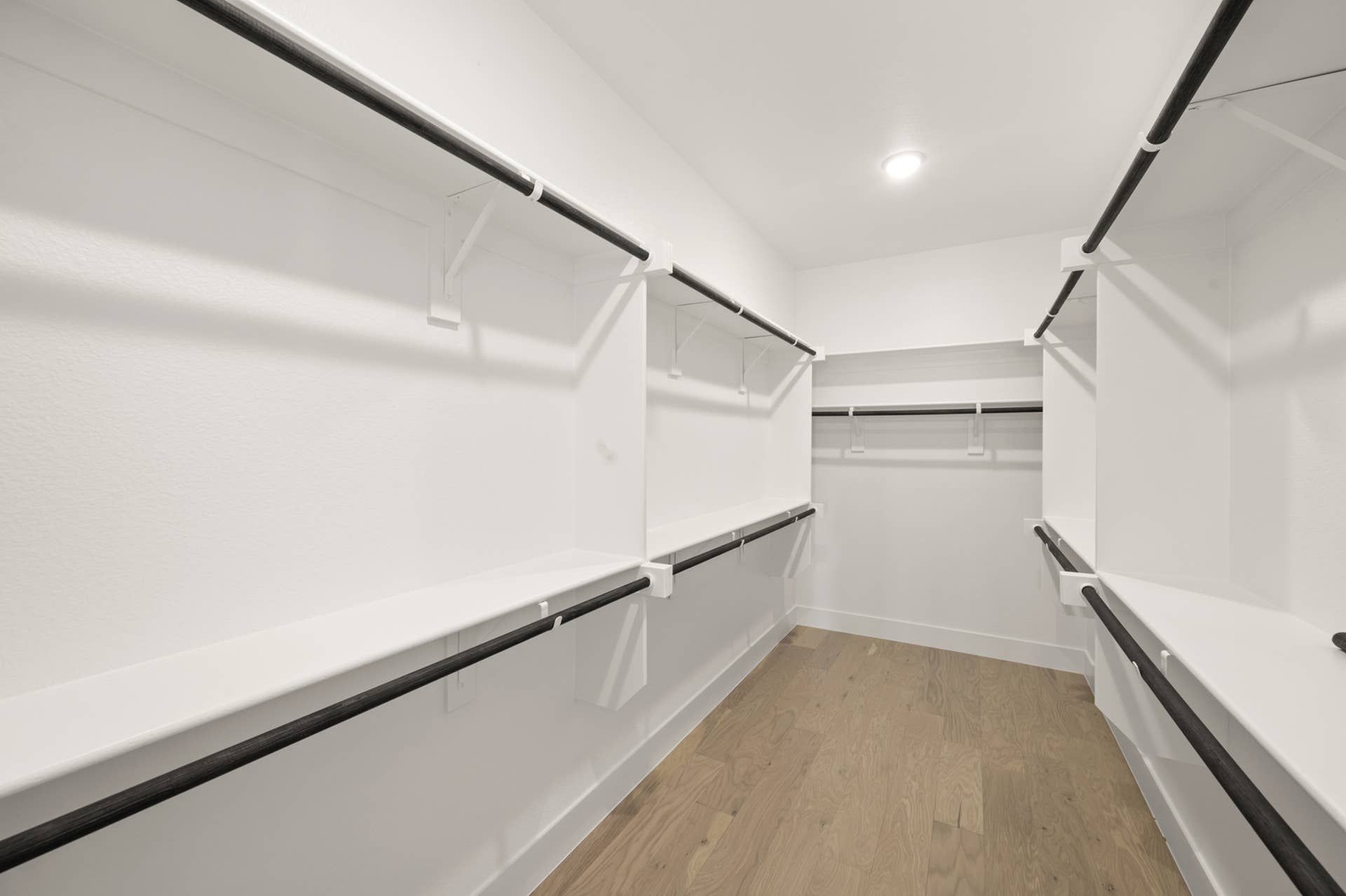 Spacious walk-in closet with wooden floors and ample hanging space.