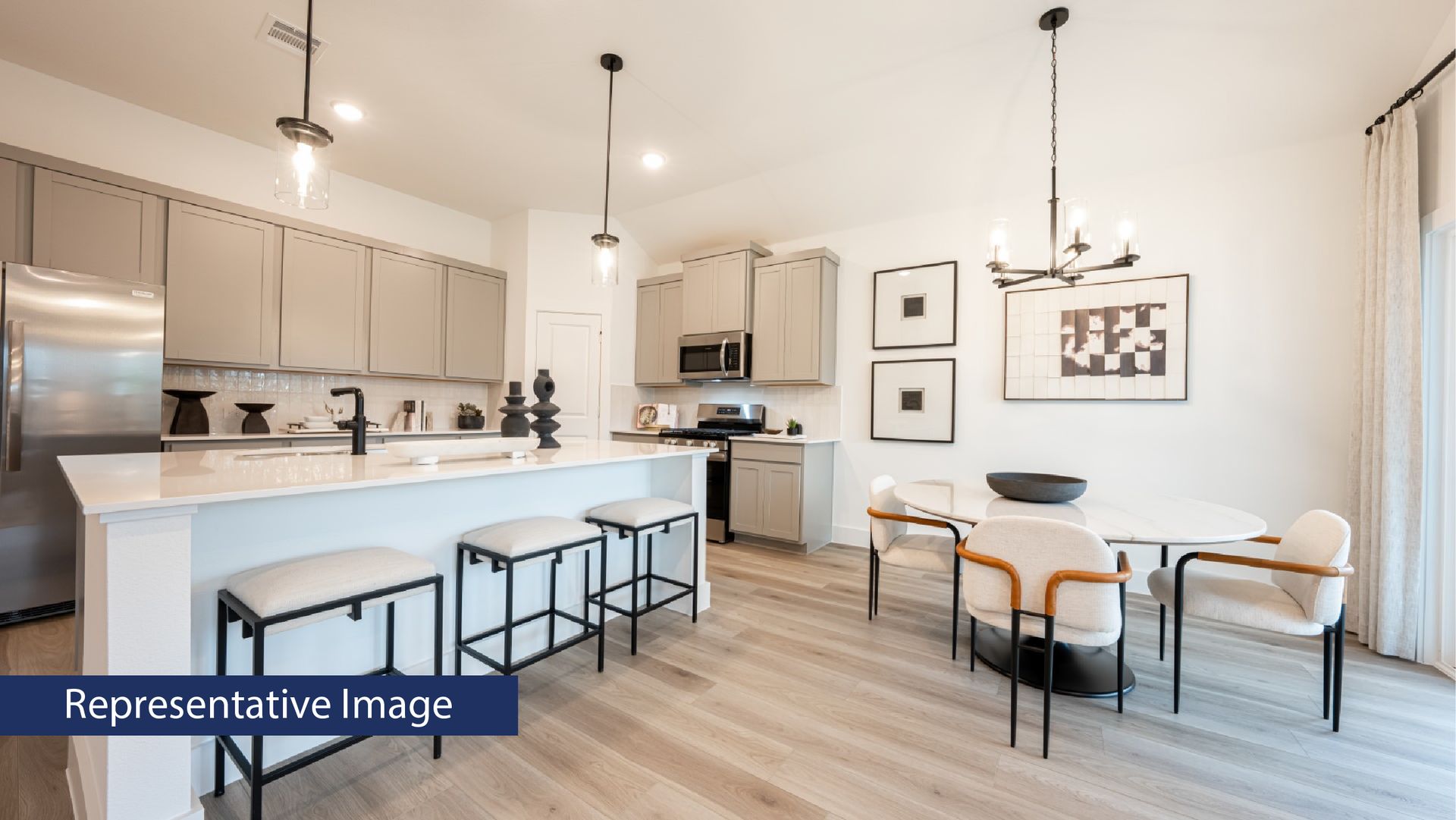 Modern kitchen and dining area with light wood flooring and gray cabinets.