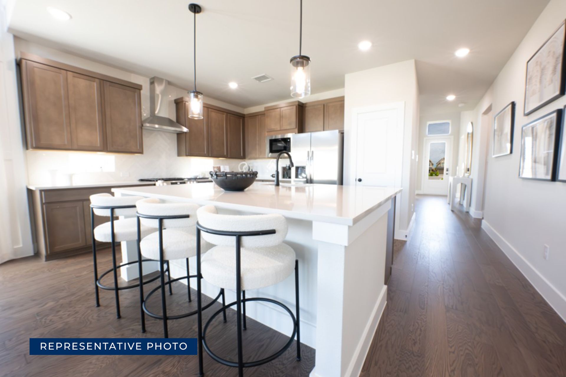 Modern kitchen with island, bar stools, and stainless steel appliances.