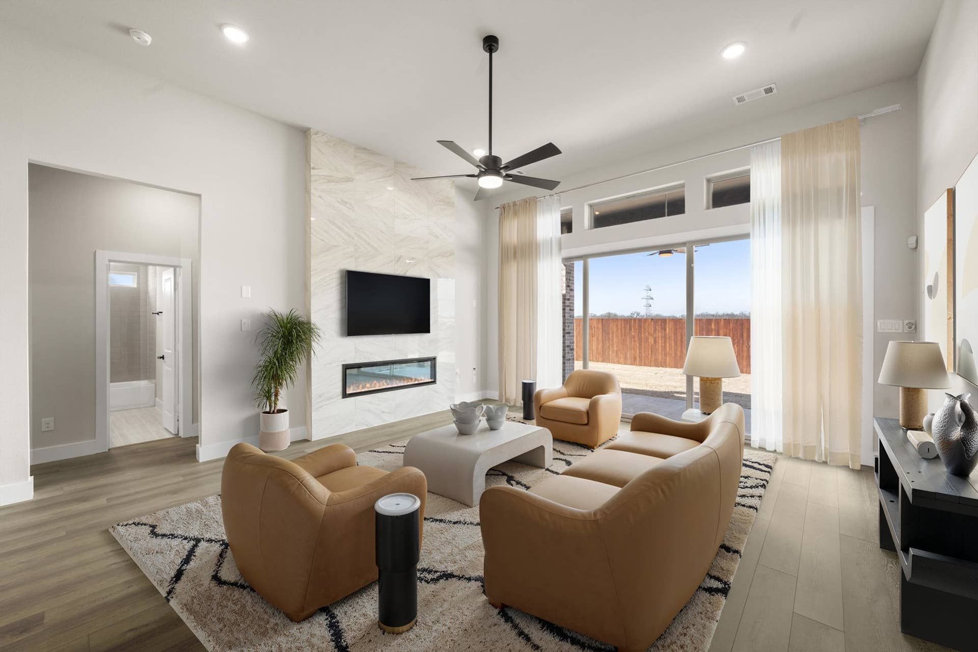 Modern living room with leather chairs, fireplace, and large window view.