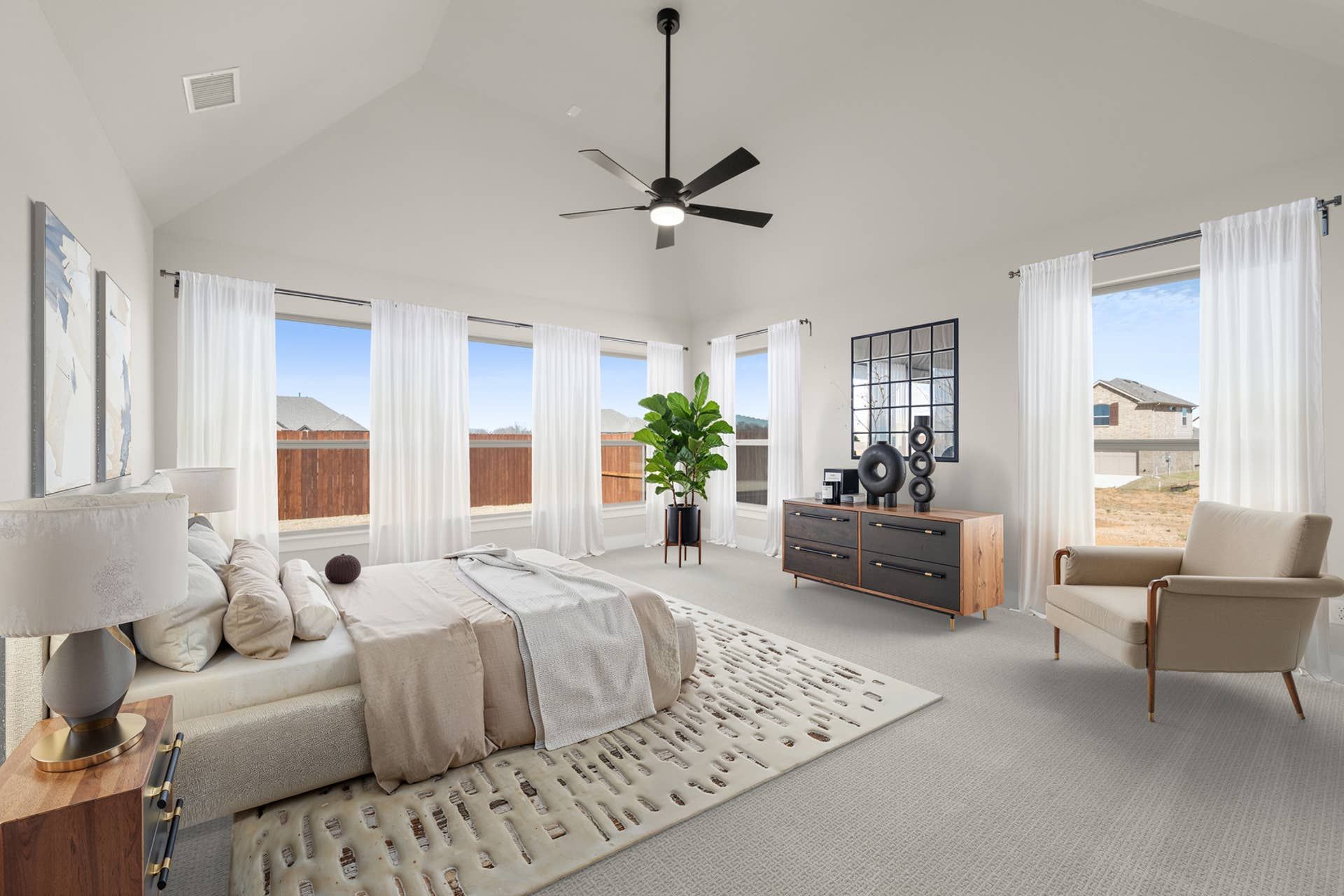 Spacious bedroom with large windows, modern decor, and ceiling fan.