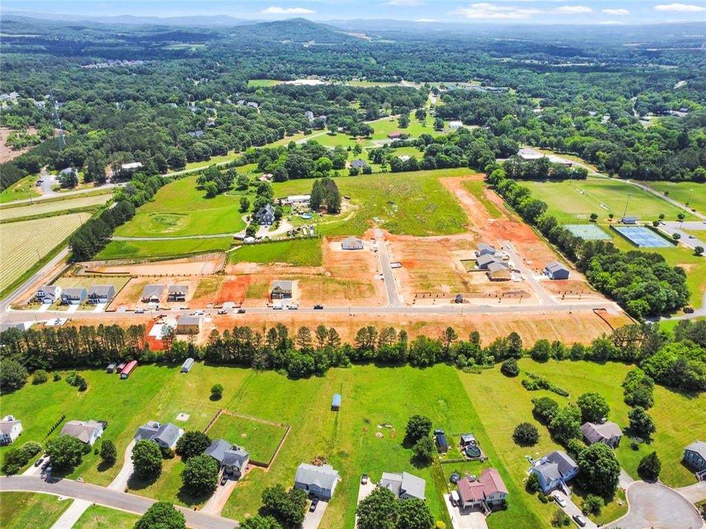 Expansive development land featuring multiple new construction homes, surrounding mature trees, and existing residential properties