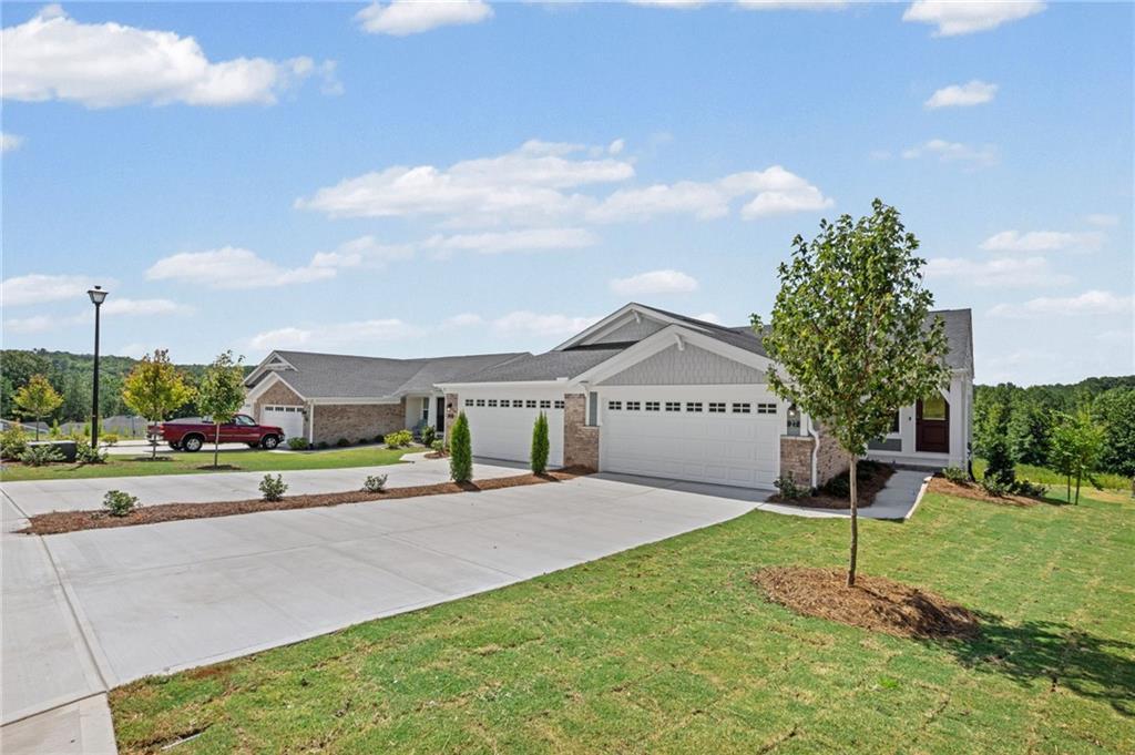 Contemporary exterior design featuring brick and siding accents, a concrete driveway, attached two-car garages with panel doors, and landscaped grounds