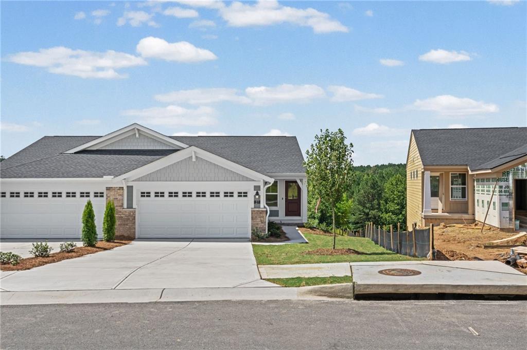 Modern siding exterior with stone accents, a two-car garage, concrete driveway, and front yard landscaping