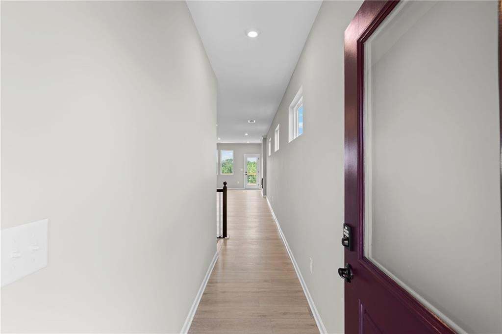 Long hallway featuring wood-finish flooring, recessed lighting, white walls, and clerestory windows