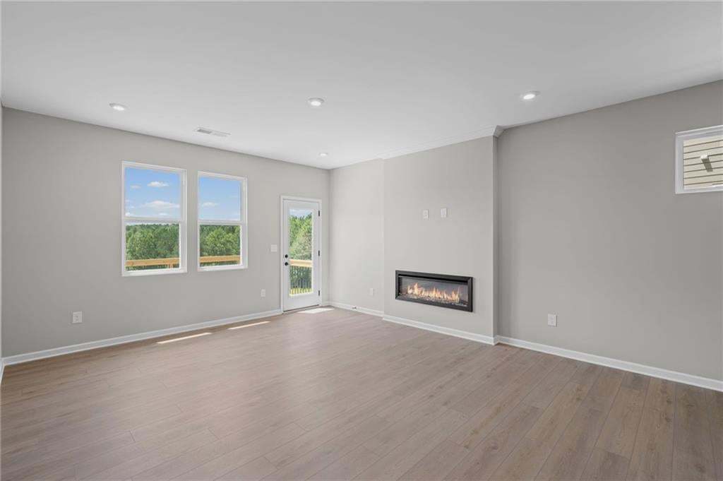 Recessed lighting, wood-finish flooring, multiple windows, glass-paneled door, and a built-in linear fireplace