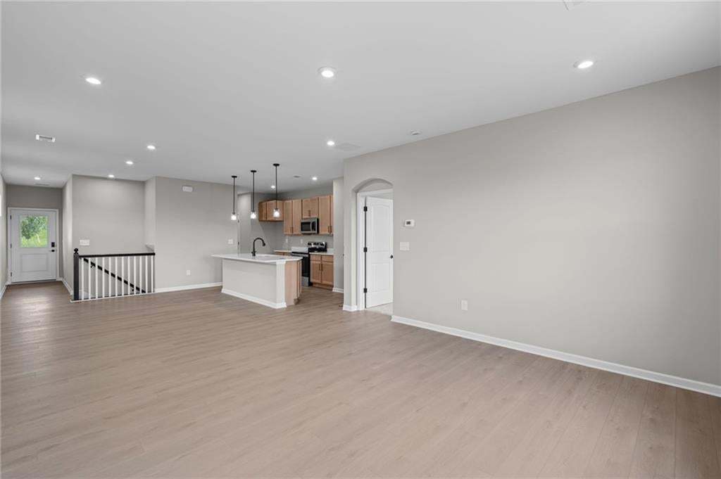 Wood-finish flooring throughout, recessed lighting, and a kitchen island with pendant lighting