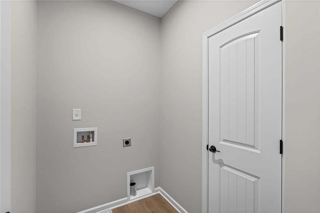 Laundry area featuring a utility hookup, power outlet, wall-mounted electrical outlet, and wood-finish flooring