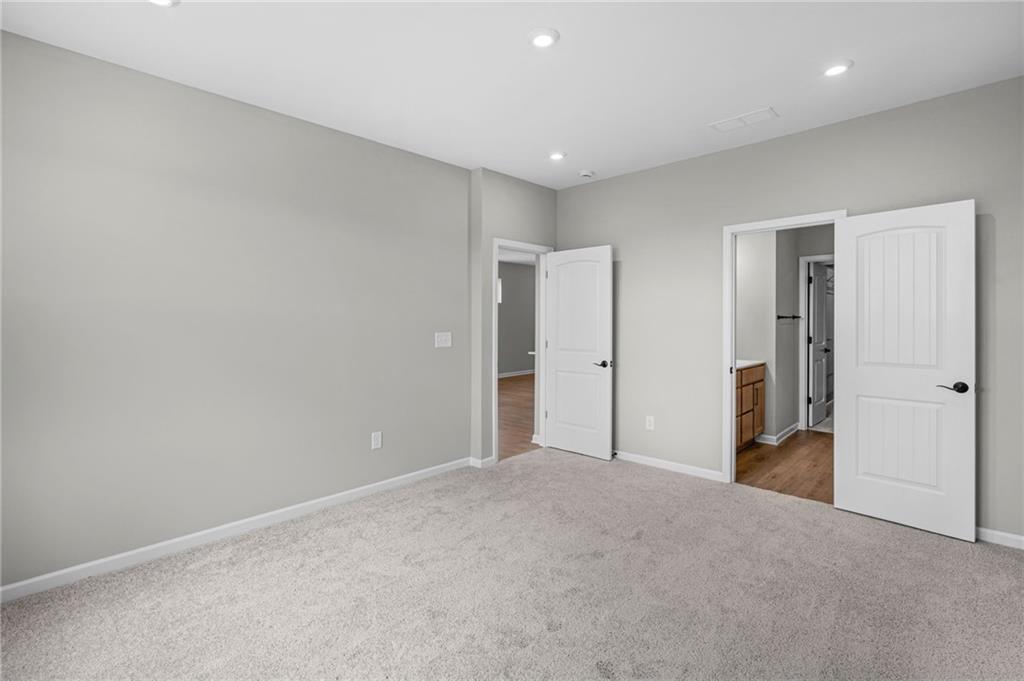 Recessed lighting, light gray wall paint, and gray carpeted flooring