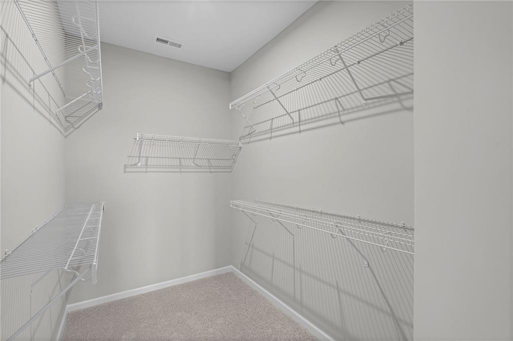 Walk-in closet featuring light gray walls, light-colored carpeting, and white wire shelving