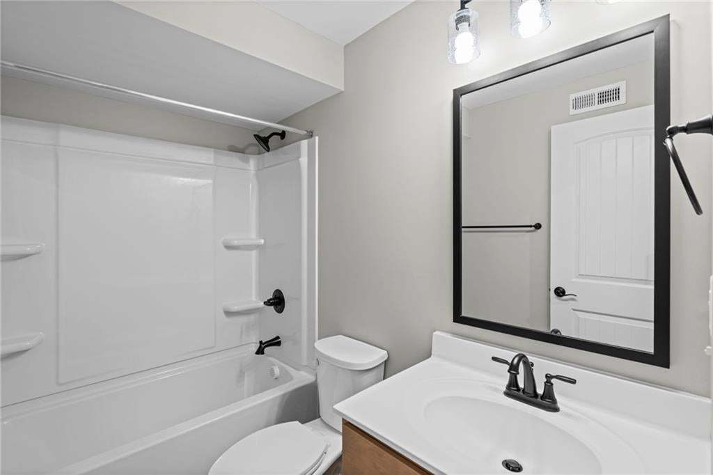 White bathtub with integral wall surround, matte black shower fixtures, vanity with white countertop, integrated sink, and matte black faucet, and a large framed wall mirror