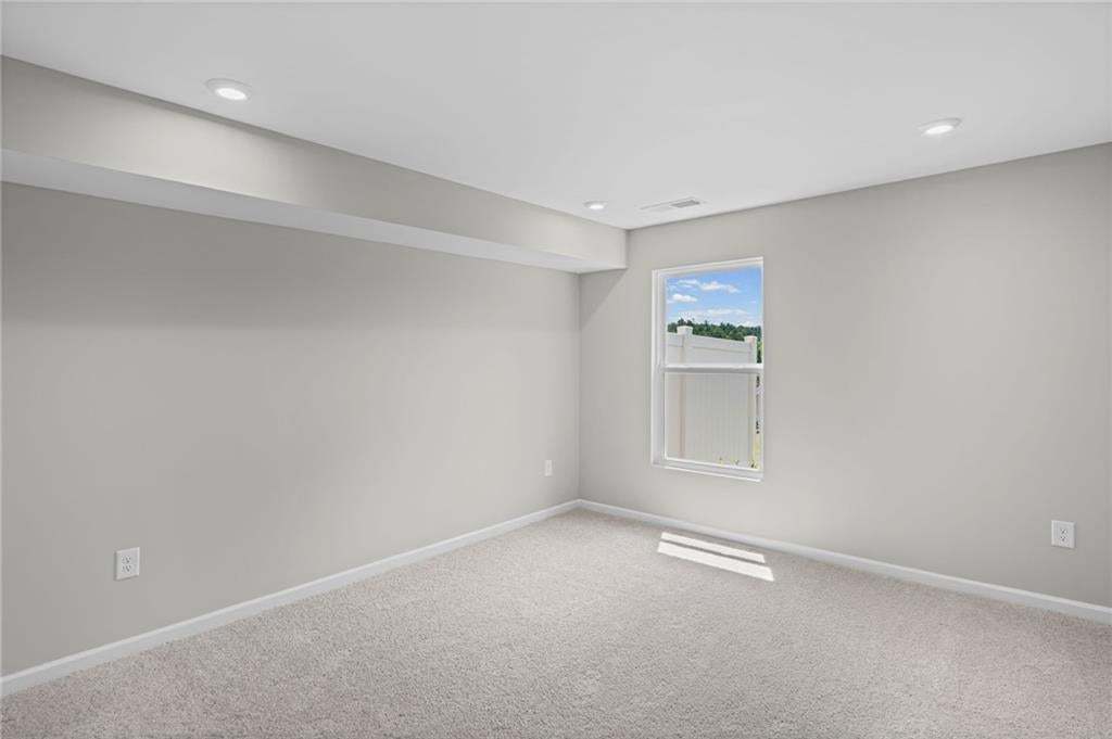 Recessed ceiling lighting, light gray wall finishes, light-colored carpeting, white trim, and a window with white framing