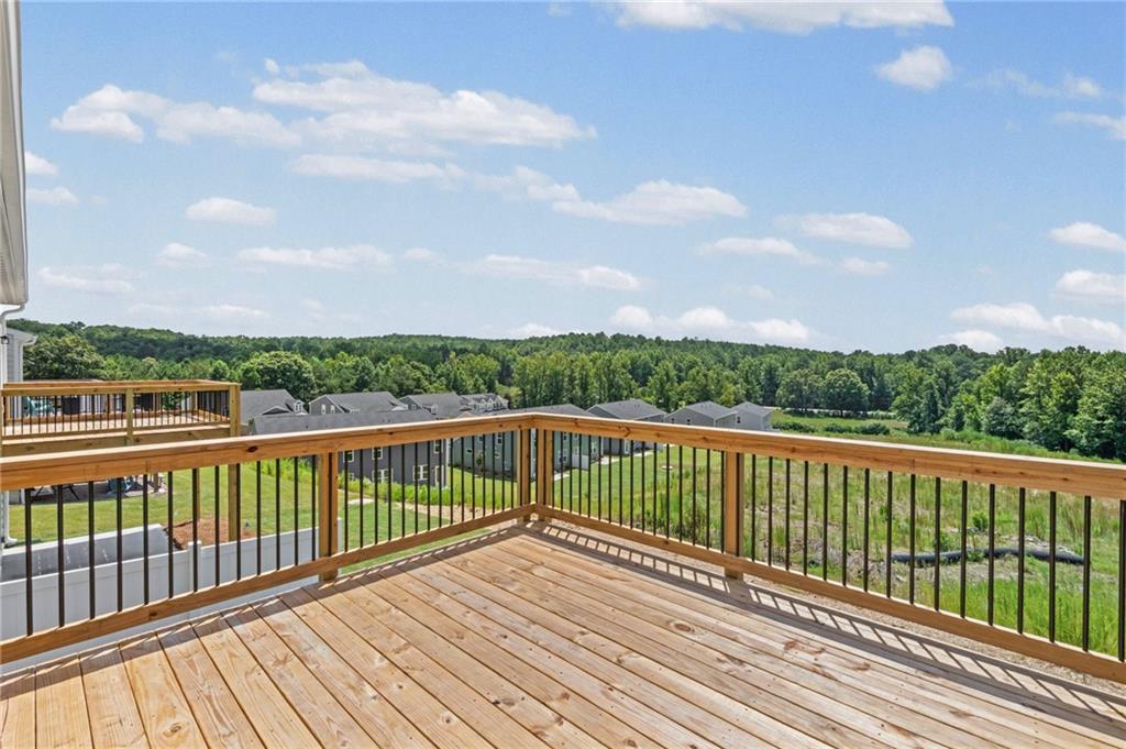 Expansive wood deck with wood and black metal railings, offering an elevated perspective of the surrounding landscape