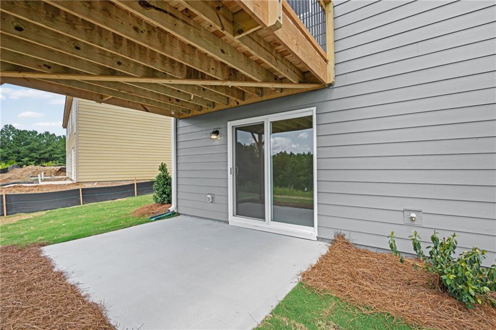 Covered patio with a concrete slab, sliding glass door, and gray horizontal siding