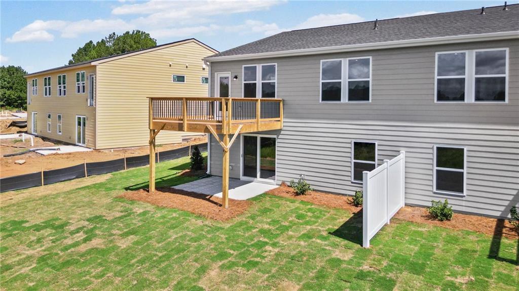 Expansive backyard with a newly installed wooden deck, gray siding exterior, and a privacy fence