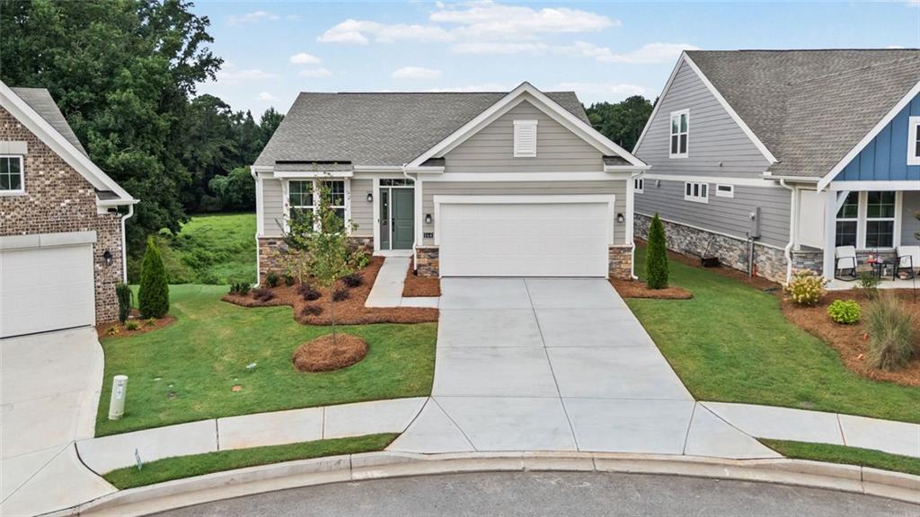 Single-story residence featuring light gray siding, stone veneer accents, and a two-car attached garage