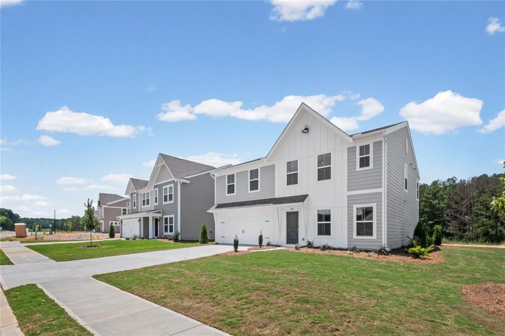 Modern farmhouse-style exterior featuring a white board-and-batten facade, gray horizontal siding, and a prominent gable roofline