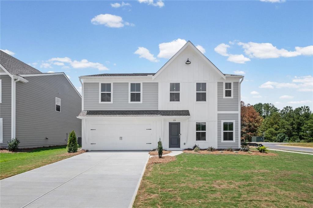 Contemporary two-story residence featuring a two-car garage, gray horizontal siding, white board and batten accents, a dark gray entry door, and a concrete driveway