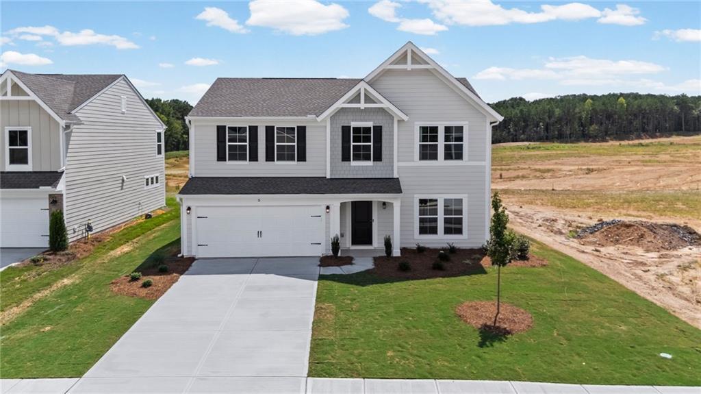 Two-story residence featuring light gray siding, black window shutters, a two-car garage, and a concrete driveway