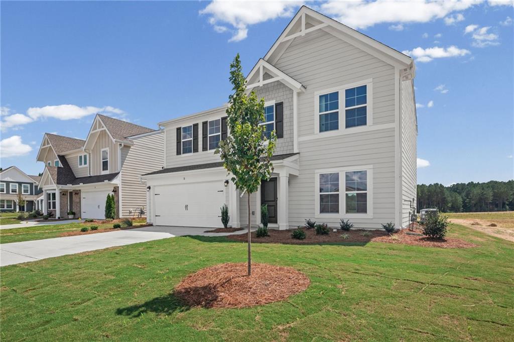 Two-story residence featuring light gray siding, white trim, and a prominent gable roofline