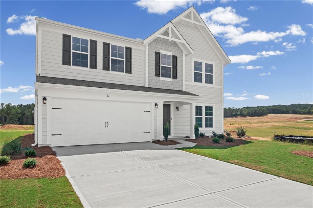 Two-story residence featuring light gray siding, dark window shutters, a two-car garage, and a concrete driveway