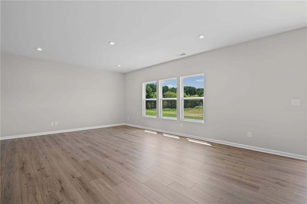 Recessed ceiling lighting, wood-finish flooring, white trim, and multiple windows