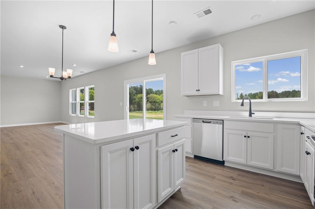 Open-concept living space with wood-finish flooring, a kitchen island, white cabinetry, and stainless steel appliances